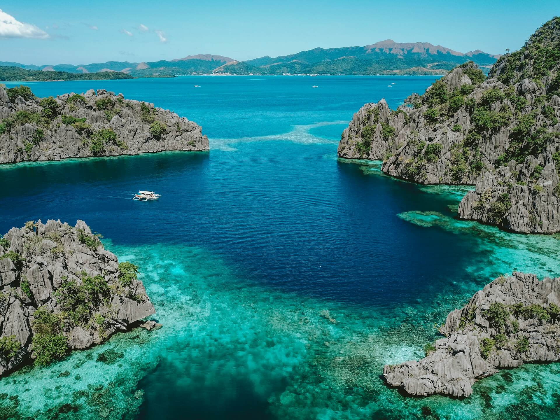 Aerial photo of clear blue sea surrounded by mountains in the Philippines